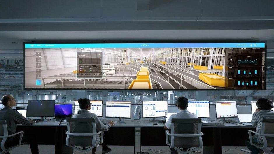 Operators seated at their screens, facing a large supervision display in a control room
